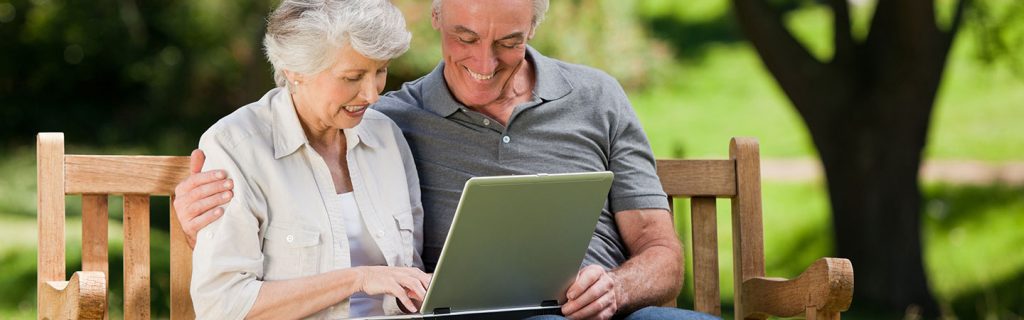 Couple using laptop on park bench